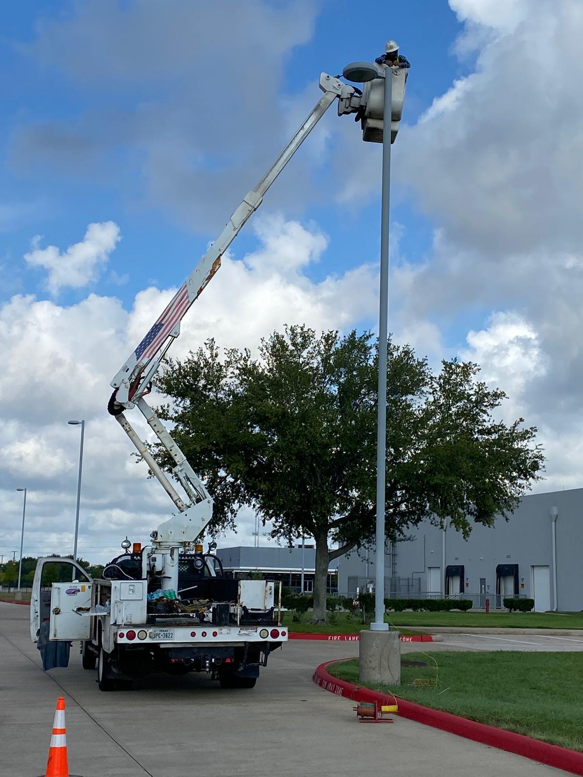 Electrician in a bucket truck working on outdoor lighting